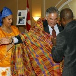 M. Ghislain Picard, Chef régional de l’Assemblée des Premières Nations, Québec/Labrador, revêt la tenue traditionnelle, aidé par M. Georges Konan et Johanne